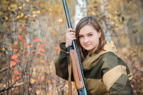 Retrato de uma bela jovem caçadora em roupas de camuflagem na floresta caduca na natureza com uma arma — Fotografia de Stock