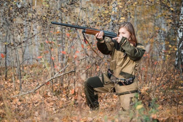 Retrato de una hermosa joven cazadora en ropa de camuflaje en el bosque caducifolio en la naturaleza con una pistola — Foto de Stock