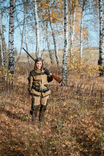Yaprak döken orman silahla doğada kamuflaj giysili bir güzel genç kız avcı portresi — Stok fotoğraf