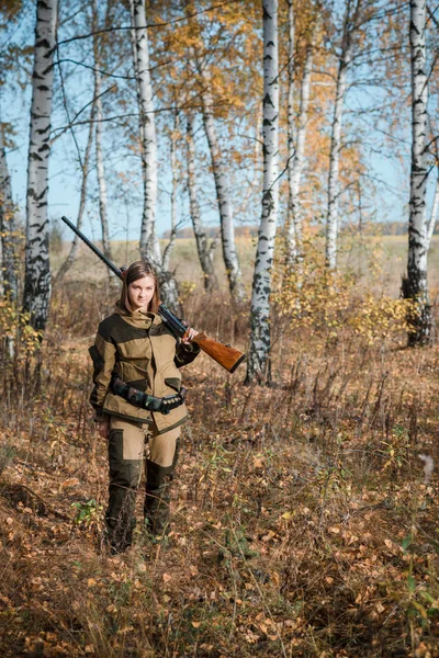 Retrato de uma bela jovem caçadora em roupas de camuflagem na floresta caduca na natureza com uma arma — Fotografia de Stock