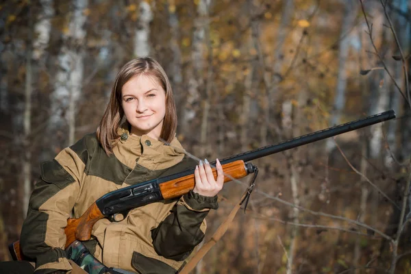 Portrait of a beautiful young girl hunter in camouflage clothes in the deciduous forest in nature with a gun — Stock Photo, Image