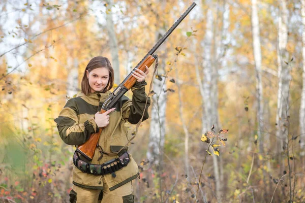 Portrait of a beautiful young girl hunter in camouflage clothes in the deciduous forest in nature with a gun — Stock Photo, Image