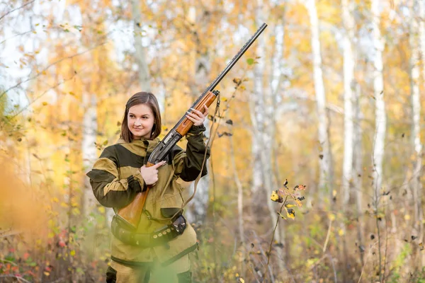 Retrato de una hermosa joven cazadora en ropa de camuflaje en el bosque caducifolio en la naturaleza con una pistola — Foto de Stock