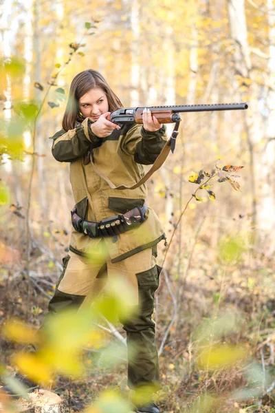 Retrato de una hermosa joven cazadora en ropa de camuflaje en el bosque caducifolio en la naturaleza con una pistola — Foto de Stock