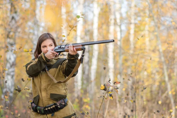 Retrato de una hermosa joven cazadora en ropa de camuflaje en el bosque caducifolio en la naturaleza con una pistola — Foto de Stock