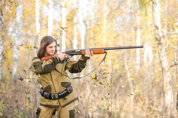 Portrait of a beautiful young girl hunter in camouflage clothes in the deciduous forest in nature with a gun — Stock Photo, Image