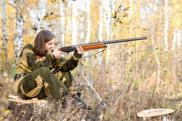 Retrato de una hermosa joven cazadora en ropa de camuflaje en el bosque caducifolio en la naturaleza con una pistola — Foto de Stock