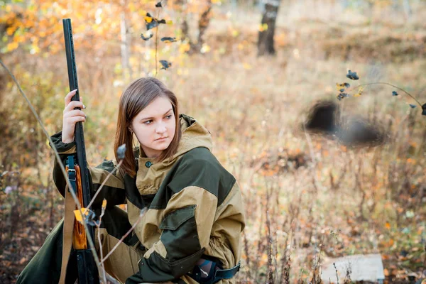 Retrato de uma bela jovem caçadora em roupas de camuflagem na floresta caduca na natureza com uma arma — Fotografia de Stock