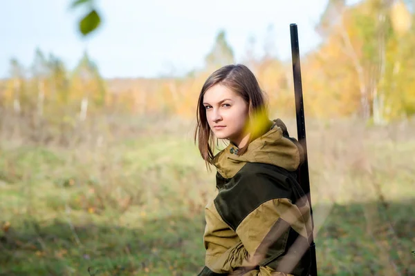 Retrato de uma bela jovem caçadora em roupas de camuflagem na floresta caduca na natureza com uma arma — Fotografia de Stock