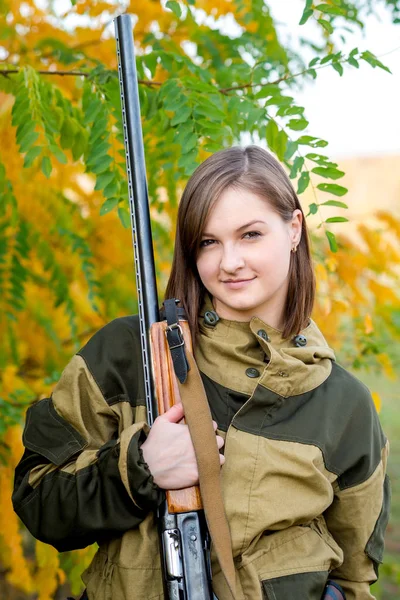 Портрет красивой молодой девушки-охотницы в камуфляжной одежде в лиственном лесу на природе с пистолетом — стоковое фото