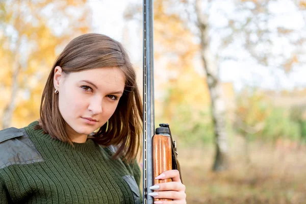 Ritratto di una bella giovane cacciatrice in abiti mimetici nella foresta decidua in natura con una pistola — Foto Stock