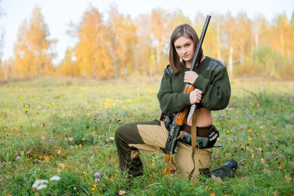 Portrait of a beautiful young girl hunter in camouflage clothes in the deciduous forest in nature with a gun — Stock Photo, Image