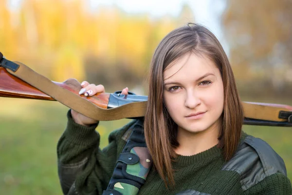 Ritratto di una bella giovane cacciatrice in abiti mimetici nel bosco con una pistola all'aperto — Foto Stock