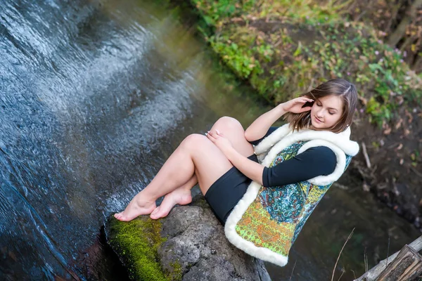 Portret van een mooi jong meisje in modieuze kleding op een achtergrond van de natuur — Stockfoto