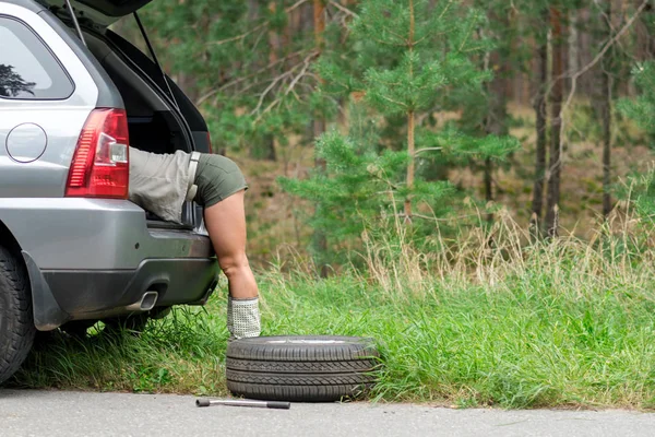 Portrét krásné mladé dívky, která opravuje rozbité auto, při pohledu do kufru klíče — Stock fotografie