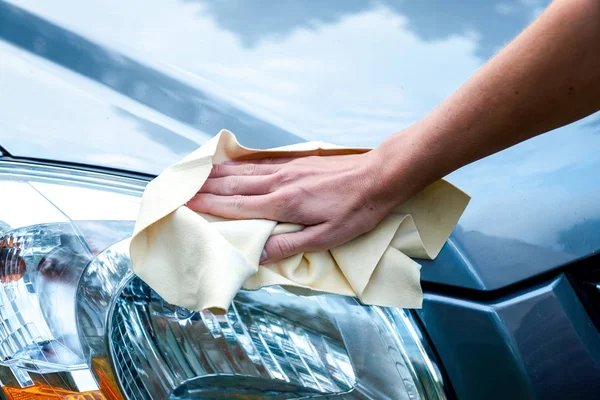 Handen van een mooi jong meisje wassen van een auto met een microfiber doek veegt koplampen en innerlijke panel van de auto, auto handwas — Stockfoto