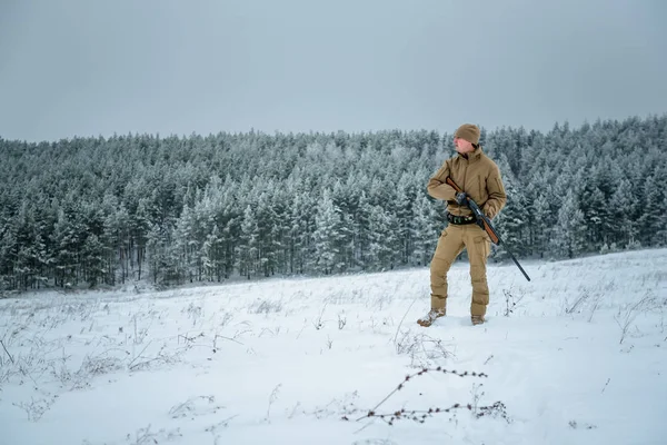 Hombre cazador vestido con ropa de camuflaje de pie en el invierno —  Fotos de Stock