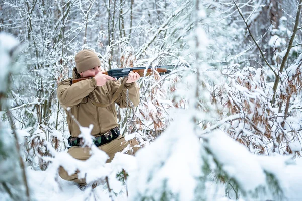 Hombre cazador vestido con ropa de camuflaje de pie en el invierno — Foto de Stock