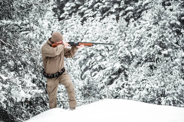 Hombre cazador vestido con ropa de camuflaje de pie en el invierno — Foto de Stock