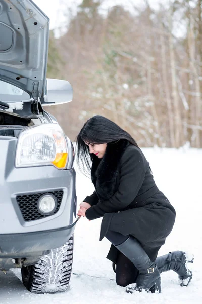 Poruchy auto v zimě. Krásná mladá dívka snaží opravit t — Stock fotografie