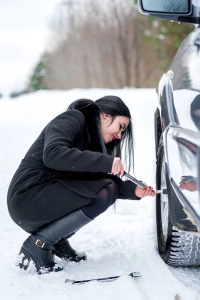 Poruchy auto v zimě. Krásná mladá dívka snaží opravit t — Stock fotografie