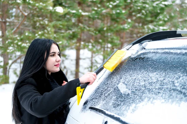 Žena čištění čelního skla auta, šťastný mladý Hrablo na sníh zima — Stock fotografie