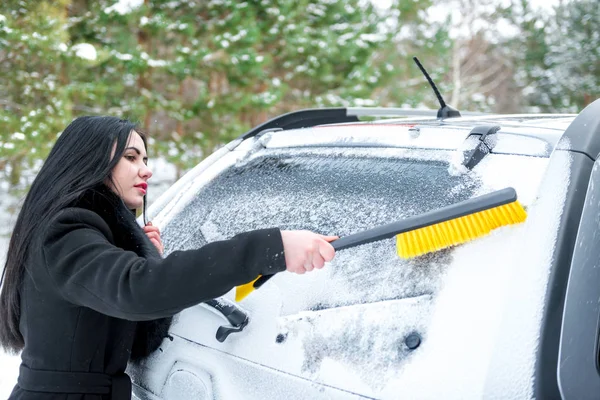 Žena čištění čelního skla auta, šťastný mladý Hrablo na sníh zima — Stock fotografie