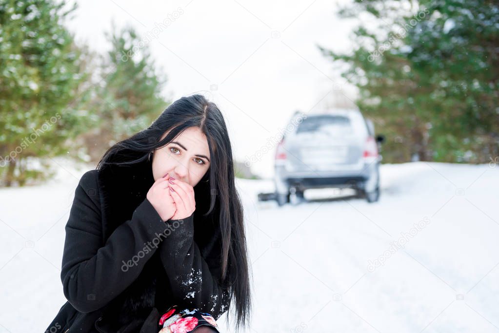 Portrait of a beautiful young girl, whose car broke down in the winter forest