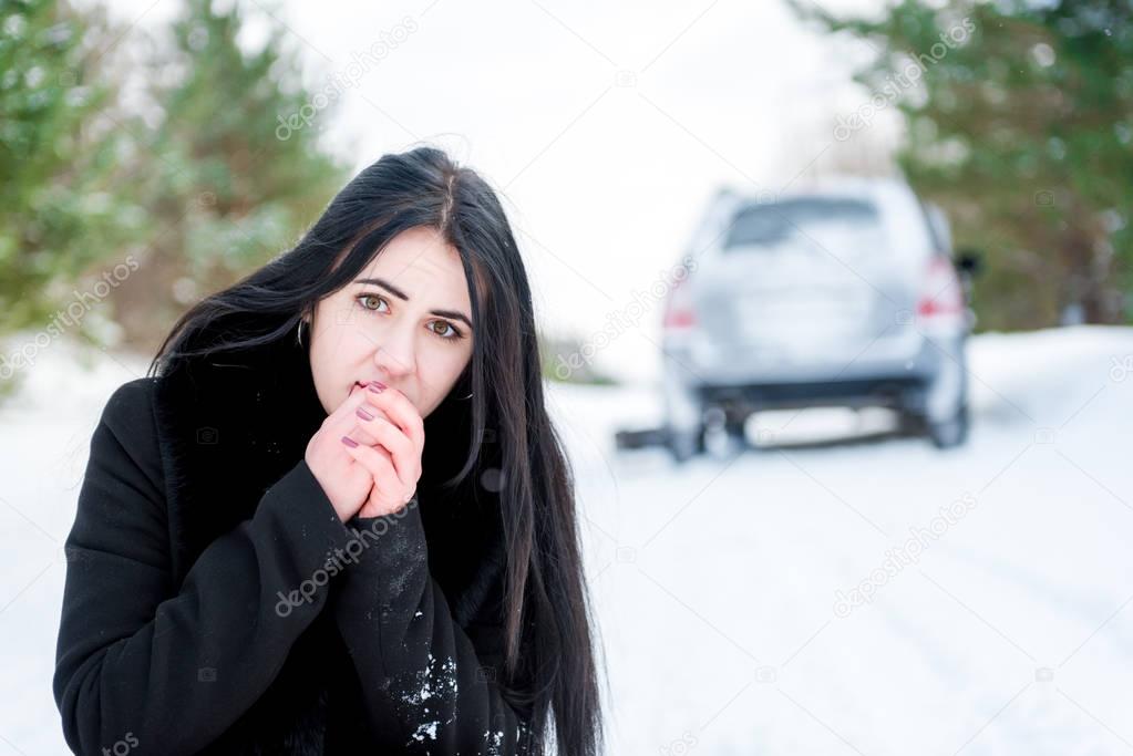 Portrait of a beautiful young girl, whose car broke down in the winter forest