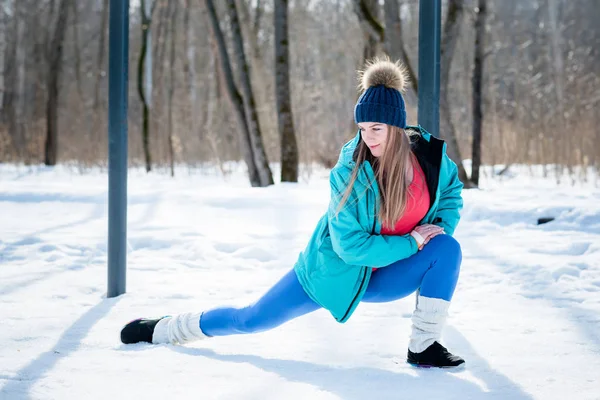 Menina bonita se estende em um campo de esportes no inverno novamente — Fotografia de Stock