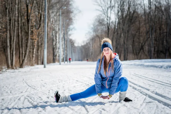 Piękna młoda dziewczyna rozciąga się na boisko sportowe w zimie ponownie — Zdjęcie stockowe