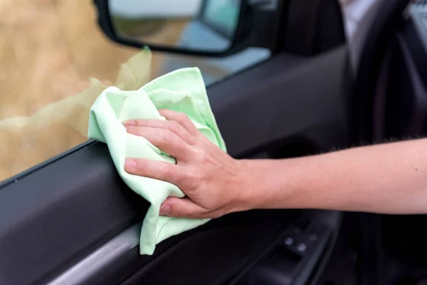 A female hand with a microfiber cloth cleans the plastic door pa