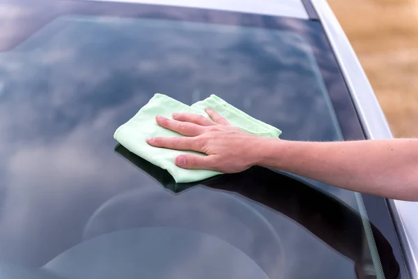 Rękę wilgotną szmatką do czyszczenia szyby samochód srebrny w sunn — Zdjęcie stockowe