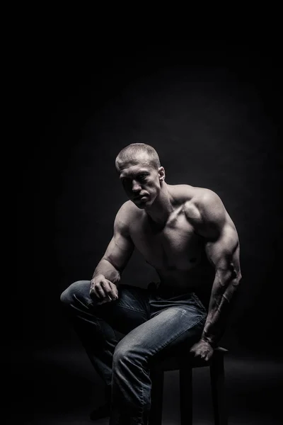 Porträtt av en sittande manliga kroppsbyggare, på en svart bakgrund-iso — Stockfoto