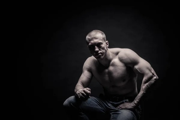 Ritratto di un bodybuilder seduto, su sfondo nero iso — Foto Stock