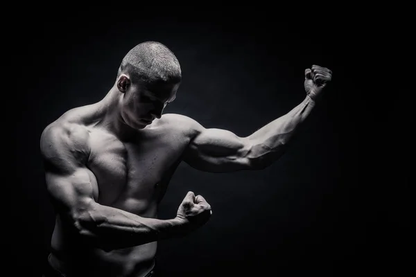 Портрет чоловіка-бодібілдера, напружує м'язи в спортивній позі — стокове фото