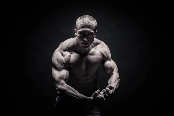 Portrait of a male bodybuilder, straining muscles in sports pose — Stock Photo, Image