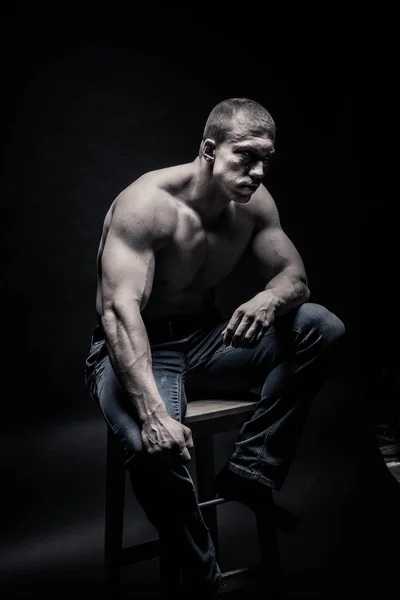 Ritratto di un bodybuilder seduto, su sfondo nero iso Fotografia Stock
