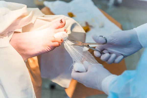 La mano del medico chirurgo, fasciando il dito del paziente Immagine Stock