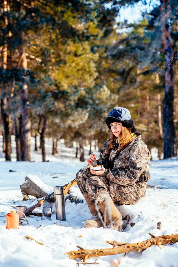 Female hunter preparing food with a portable gas burner in a win