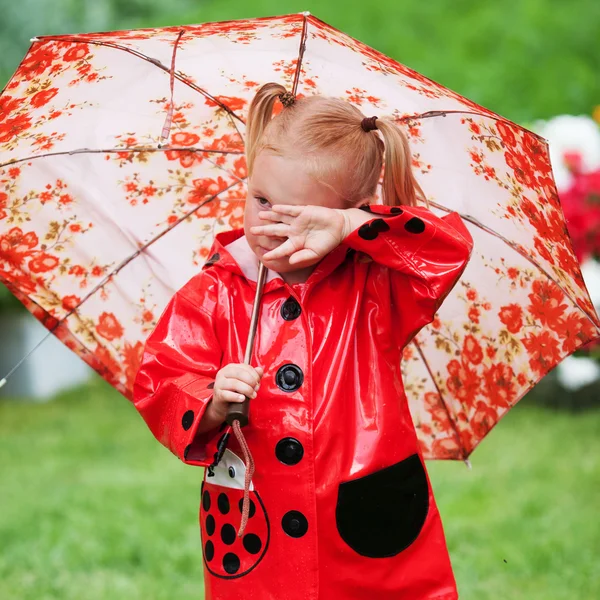 Trauriges hübsches Mädchen in rotem Regenmantel mit Regenschirm spazieren im Sommer im Park — Stockfoto