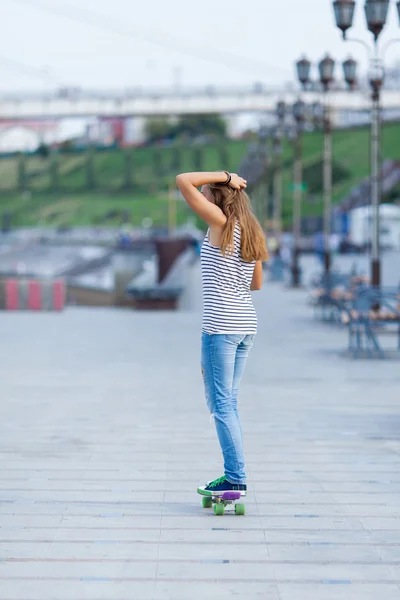 Young cute school girl rides skateboard on road — Stock Photo, Image