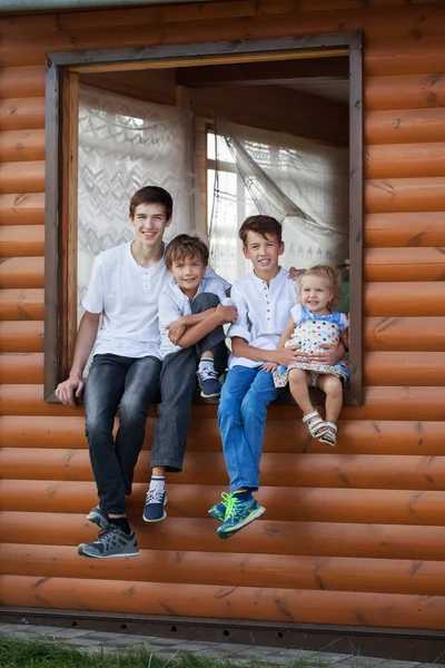 Portrait de heureux beaux garçons et petite fille sur fond de maison en bois — Photo