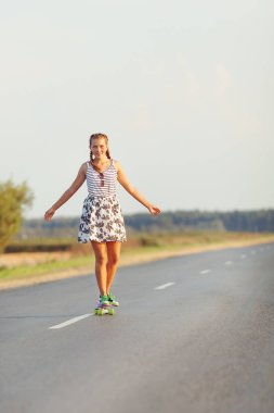 Genç sevimli kız yolda kaykay sürmek