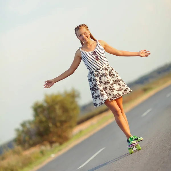 Young cute girl rides skateboard on road — Stock Photo, Image