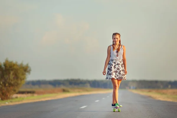 Joven linda chica paseos monopatín en la carretera — Foto de Stock