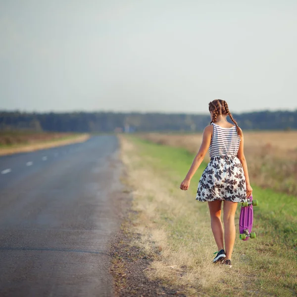 Young cute girl rides skateboard on road — Stock Photo, Image