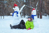 zábava, šťastné dítě hraje s sněhulák v zimě parku