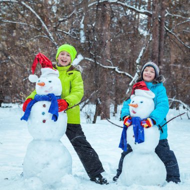 Eğlence, mutlu çocuklar kardan adam ile oynarken