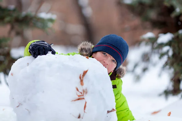 Amusement d'hiver, enfant heureux jouant avec bonhomme de neige — Photo